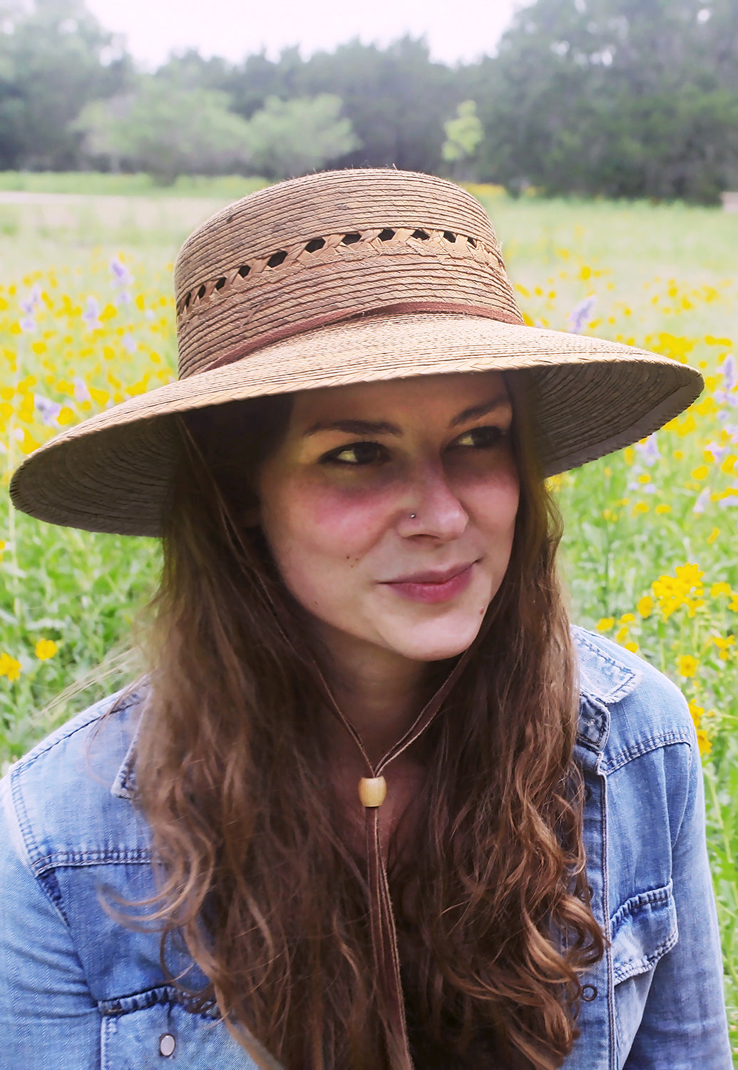 Hand-woven honey palm straw hat with lattice cutouts, wide brim, and leather chin strap on a model.