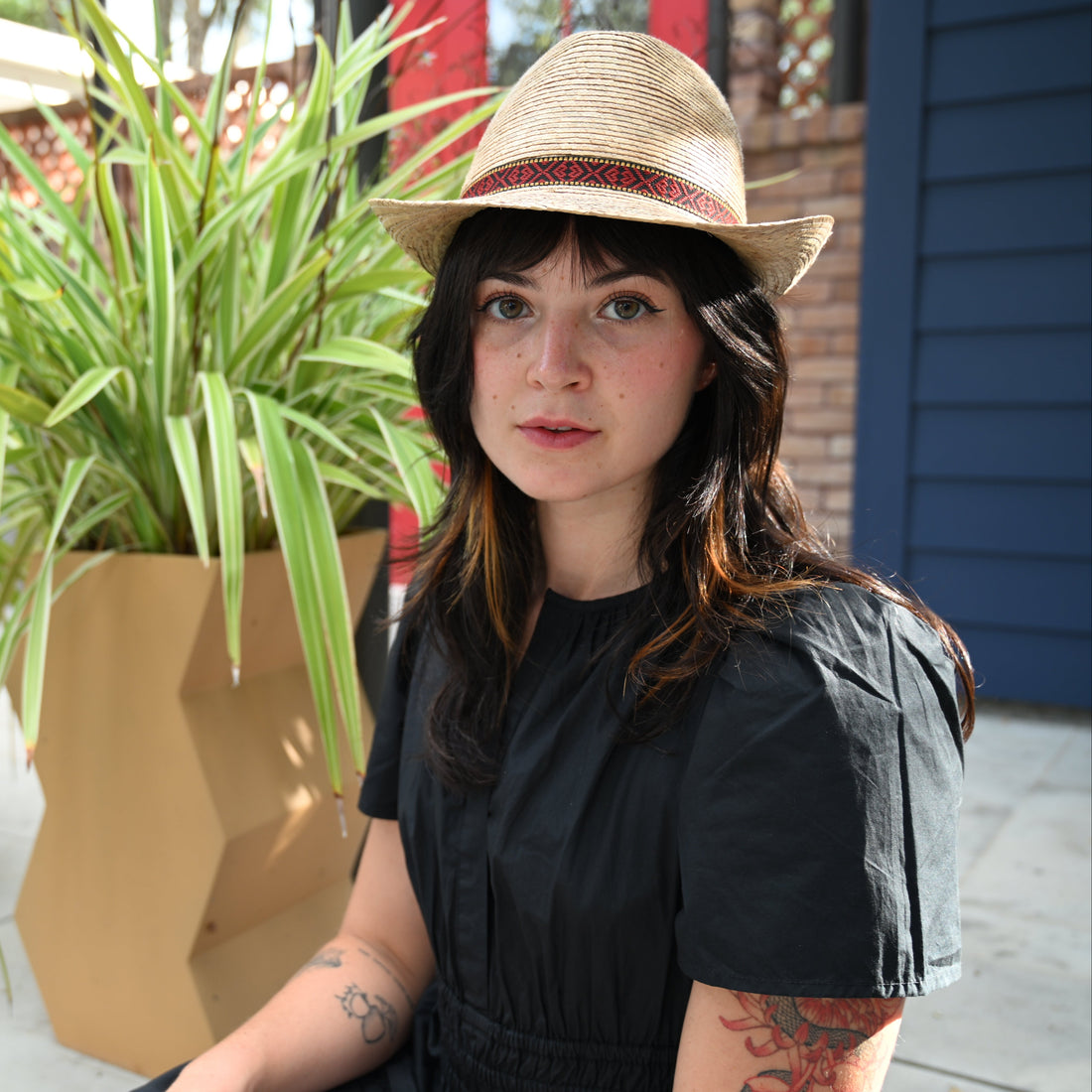 Woman wearing a straw hat standing in front of potted plants