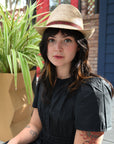 Woman wearing a straw hat standing in front of potted plants