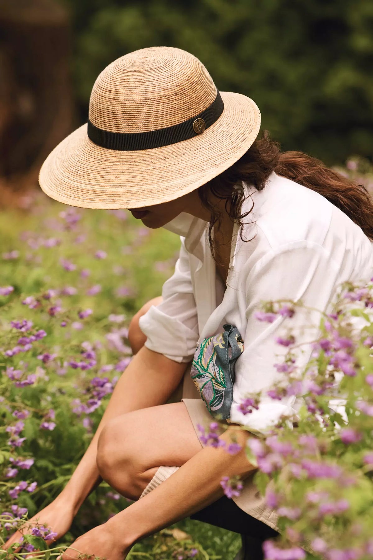 Laurel Extra Large honey palm straw hat with black band, 4.5" brim, UPF 50+ sun protection, in a field of purple flowers - model