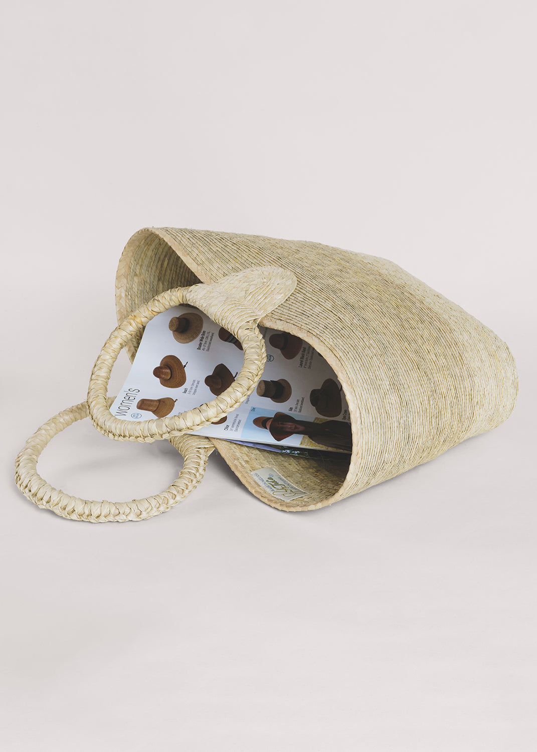 Rosita Palm Straw Tote: Hand-woven natural palm fiber tote with circular handles, light straw color.